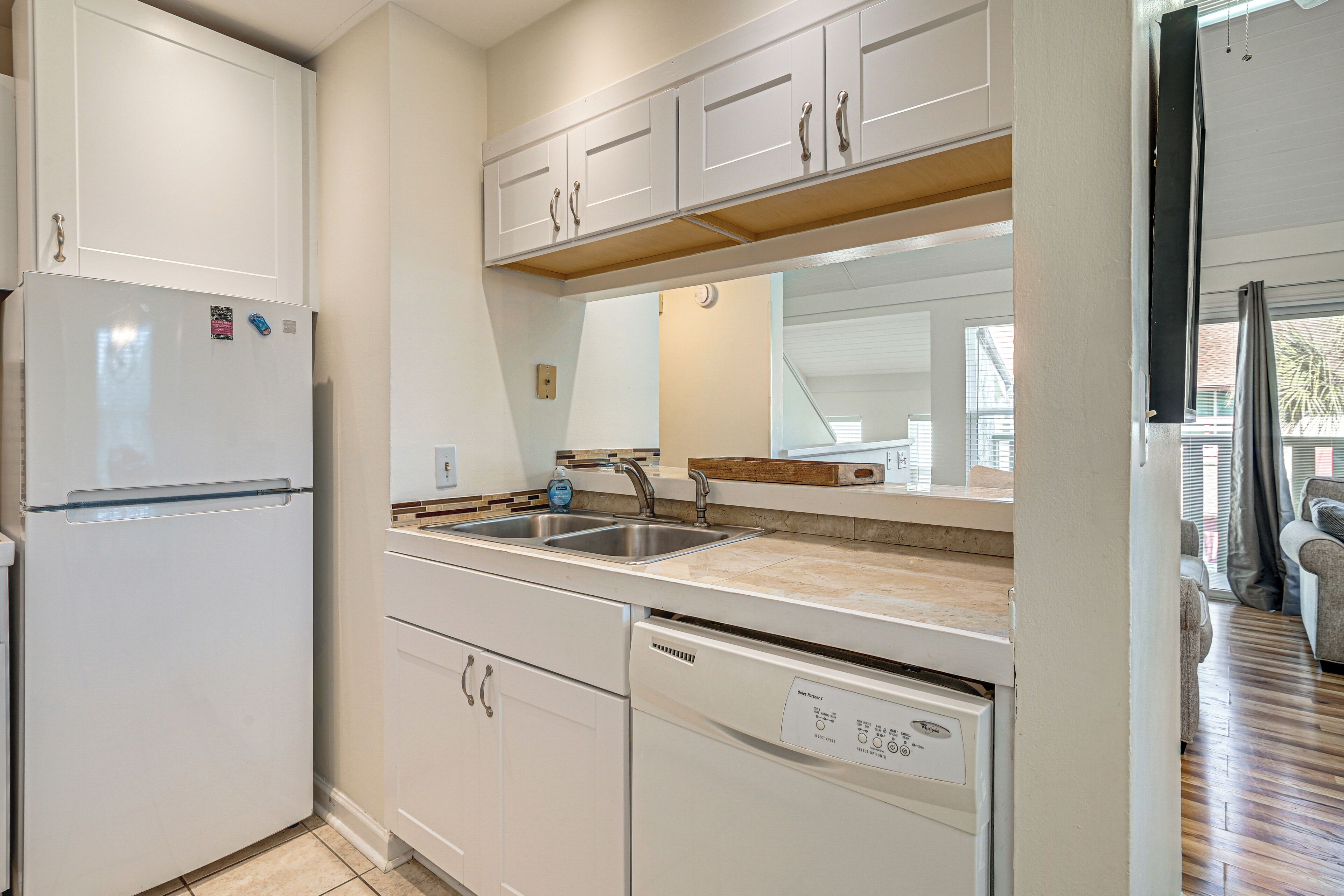 A kitchen with white cabinets, a dishwasher, and a double sink.