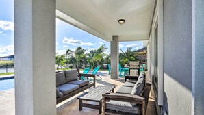 An outdoor patio area with a pool, seating, and a view of palm trees. - Stunning Laguna Vista Retreat w/ Pool & Grill (Port Isabel)