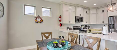 A modern kitchen with white cabinets, a central island, and a dining area with a table set for two.