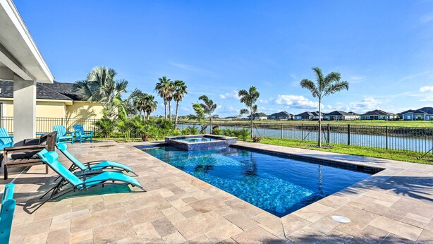 A swimming pool with lounge chairs and a hot tub, surrounded by palm trees and a view of a lake. - Stunning Laguna Vista Retreat w/ Pool & Grill (Port Isabel)