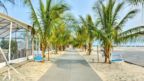 A beach walkway lined with palm trees and a covered area with signs indicating a private beach and a pool. - Private Beach Access: Wildwood Crest Retreat (Wildwood Crest)