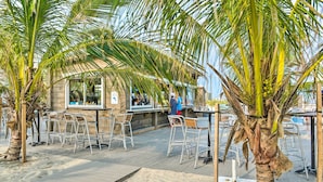 An outdoor seating area with metal chairs and tables, surrounded by palm trees. - Private Beach Access: Wildwood Crest Retreat (Wildwood Crest)