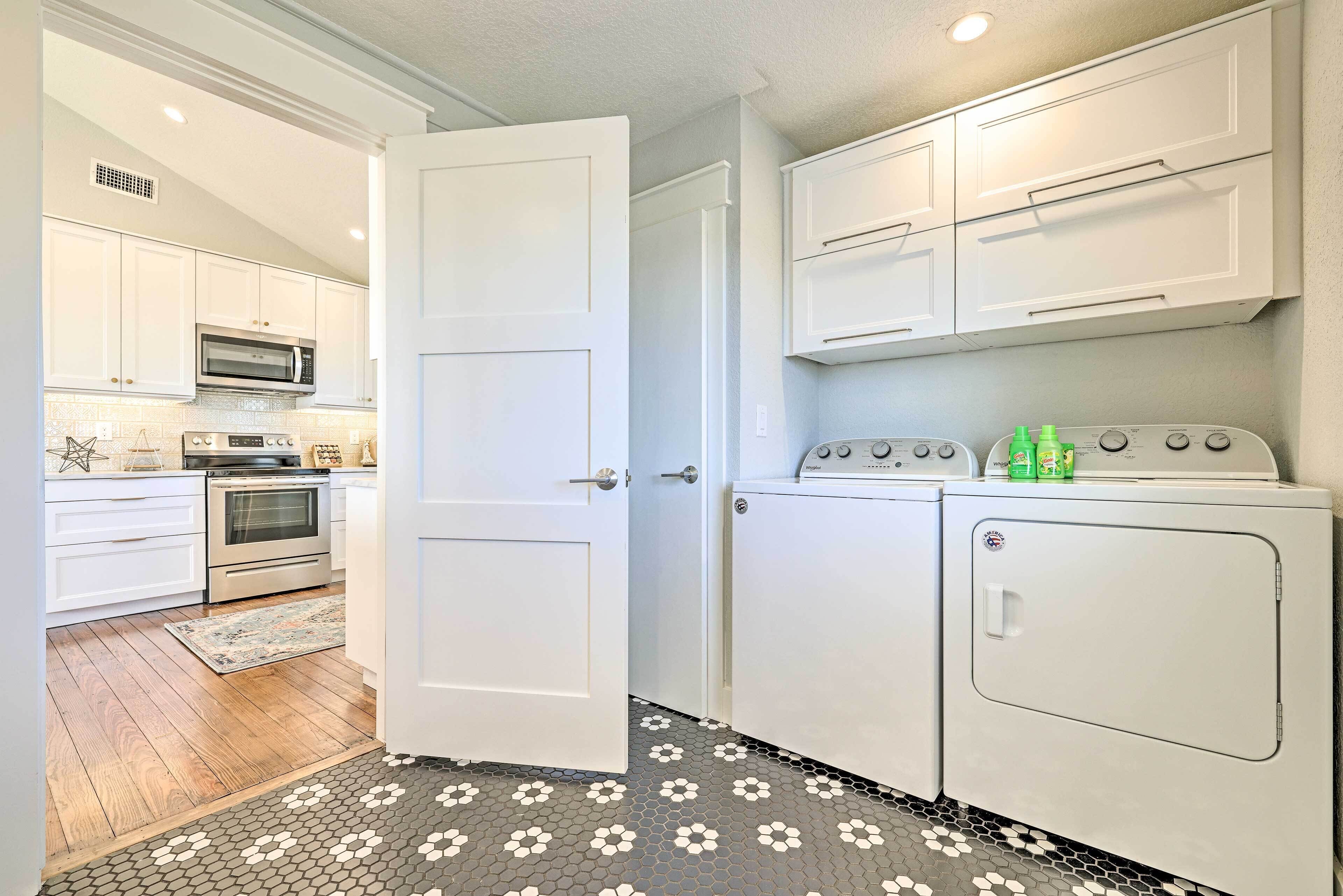 A kitchen with white cabinets, a microwave, an oven, and a washing machine.
