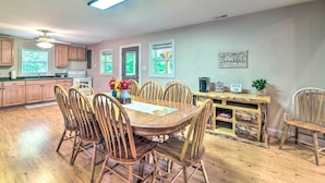 A spacious kitchen with wooden cabinets, a dining table with chairs, a ceiling fan, and a coffee station. - Secluded Brownsville Cabin w/ Deck & Fire Pit (Roundhill)