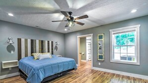 A bedroom with a bed, ceiling fan, and a large window. - Secluded Brownsville Cabin w/ Deck & Fire Pit (Roundhill)
