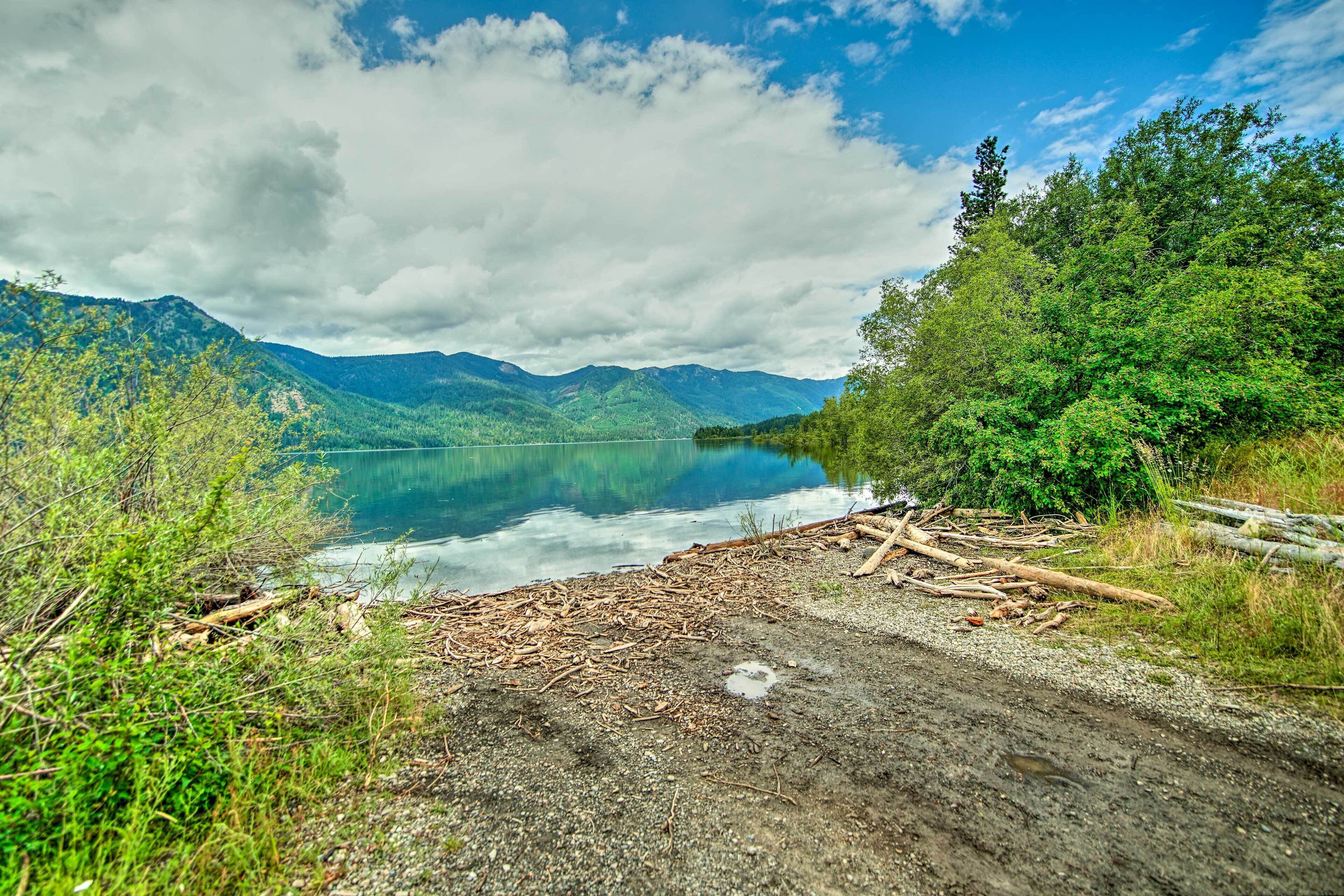 A natural landscape with a lake, mountains, and a dirt path.