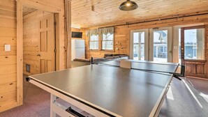 Ein Tischtennistisch in einem Holzraum mit großen Fenstern und einem Deckenventilator.