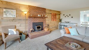 A cozy living room with a brick fireplace, a sofa, a chair, and a coffee table. - Rockaway Beach Vacation Rental: Walk to Ocean (Rockaway Beach)
