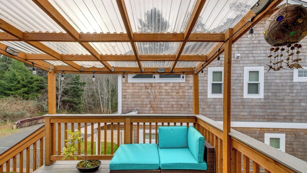 A wooden deck with a cushioned bench, a potted plant, and a hanging decoration. - Rockaway Beach Vacation Rental: Walk to Ocean (Rockaway Beach)