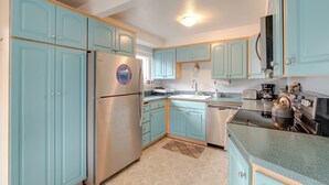 A kitchen with teal cabinets, stainless steel appliances, and a patterned rug. - Rockaway Beach Vacation Rental: Walk to Ocean (Rockaway Beach)