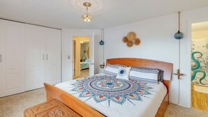 A bedroom with a wooden bed, a white ceiling, and a door leading to another room. - Rockaway Beach Vacation Rental: Walk to Ocean (Rockaway Beach)