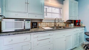 A kitchen with white cabinets, a microwave, a sink, and a coffee maker. - By Dtwn Lubbock! Spacious 4BR Home Near Texas Tech (Lubbock)