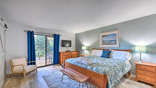 A bedroom with a bed, a bench, a chair, a TV, and a painting on the wall. - 5 Pools: Pet-friendly Palmetto Dunes Condo! (Hilton Head Island)