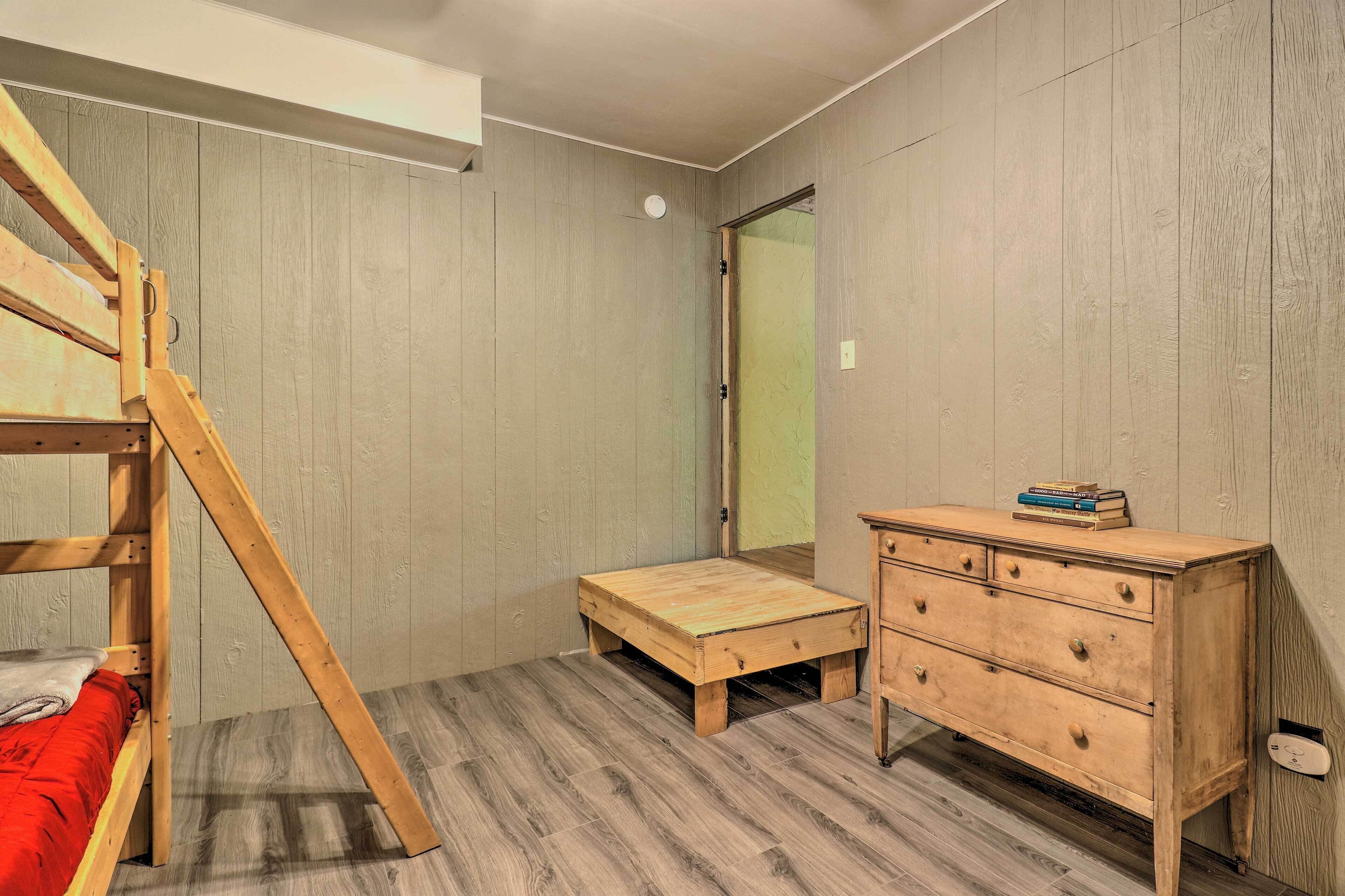 Ein Schlafzimmer mit einem Etagenbett, einem Holzkleiderschrank und einem kleinen Nachttisch.