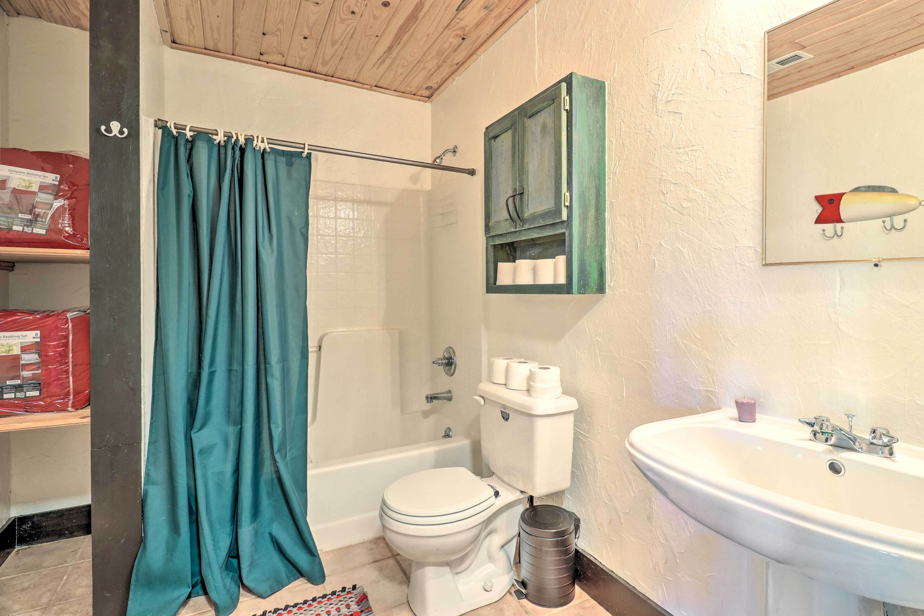 Une salle de bain avec des toilettes blanches, une baignoire, un lavabo et un rideau de douche.