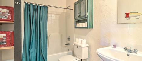 Une salle de bain avec des toilettes blanches, une baignoire, un lavabo et un rideau de douche.