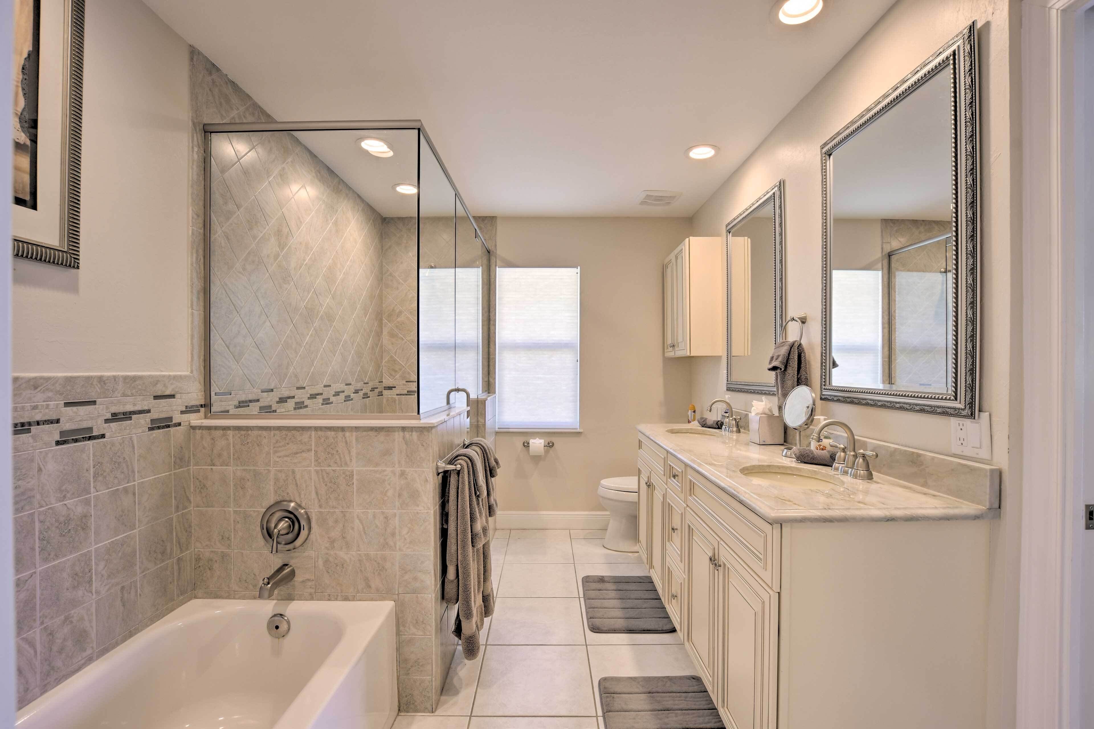 A modern bathroom with a bathtub, a toilet, a sink, and a large mirror.