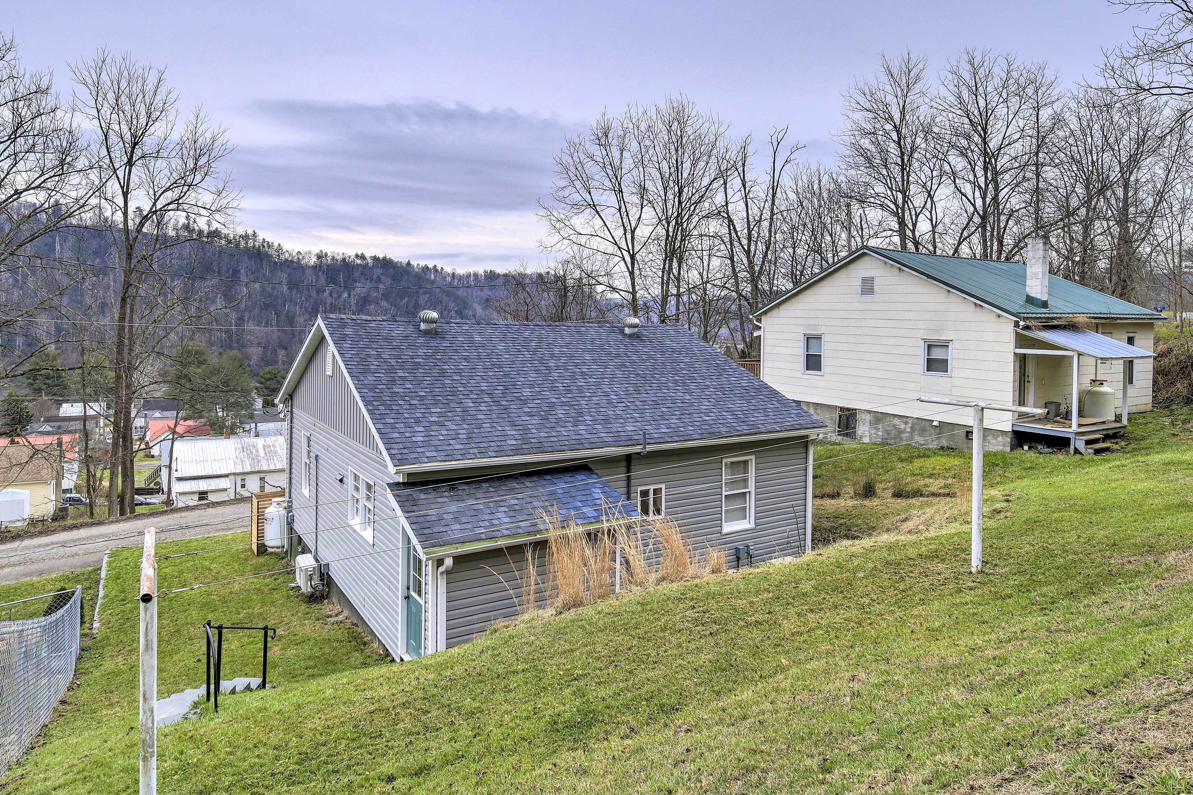 A two-story house with a sloped roof, a covered porch, and a fenced yard.