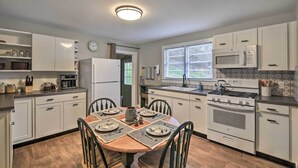 A modern kitchen with white cabinetry, a dining table set for four, and a large stove. - Cozy Fries Escape w/ Mountain & River Views! (Fries)