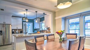 A modern kitchen with white cabinets, a stainless steel refrigerator, a central island with seating, and pendant lighting. - Bright St Petersburg Home w/ Pergola & Garden (St. Petersburg)