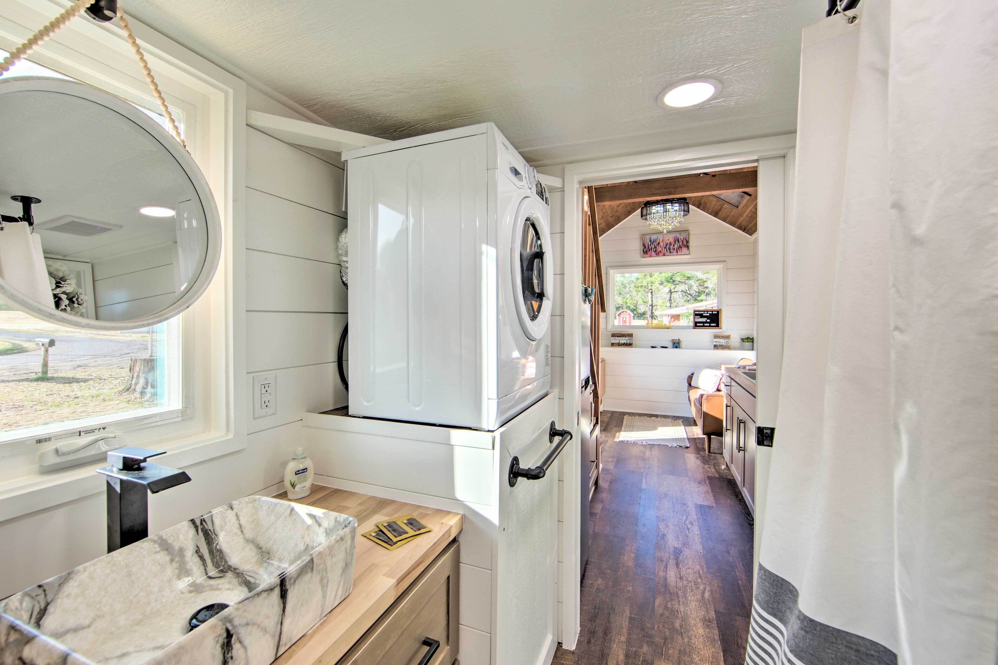 A compact kitchen with a built-in washer and dryer, a marble countertop, and a view through an open doorway to a dining area.