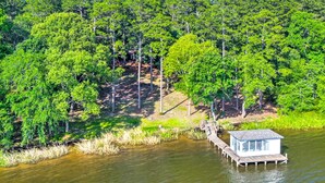 A wooden dock extending into a calm body of water, surrounded by dense green foliage.