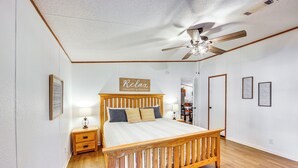 A bedroom with a wooden bed, a nightstand, a ceiling fan, and a wall-mounted sign.