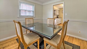 A dining area with a glass-top table and four wooden chairs with cushioned seats. - Dearborn Home w/ Games & Furnished Patio (Dearborn)