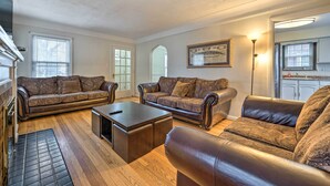 A spacious living room with leather sofas, a coffee table, and hardwood flooring. - Dearborn Home w/ Games & Furnished Patio (Dearborn)