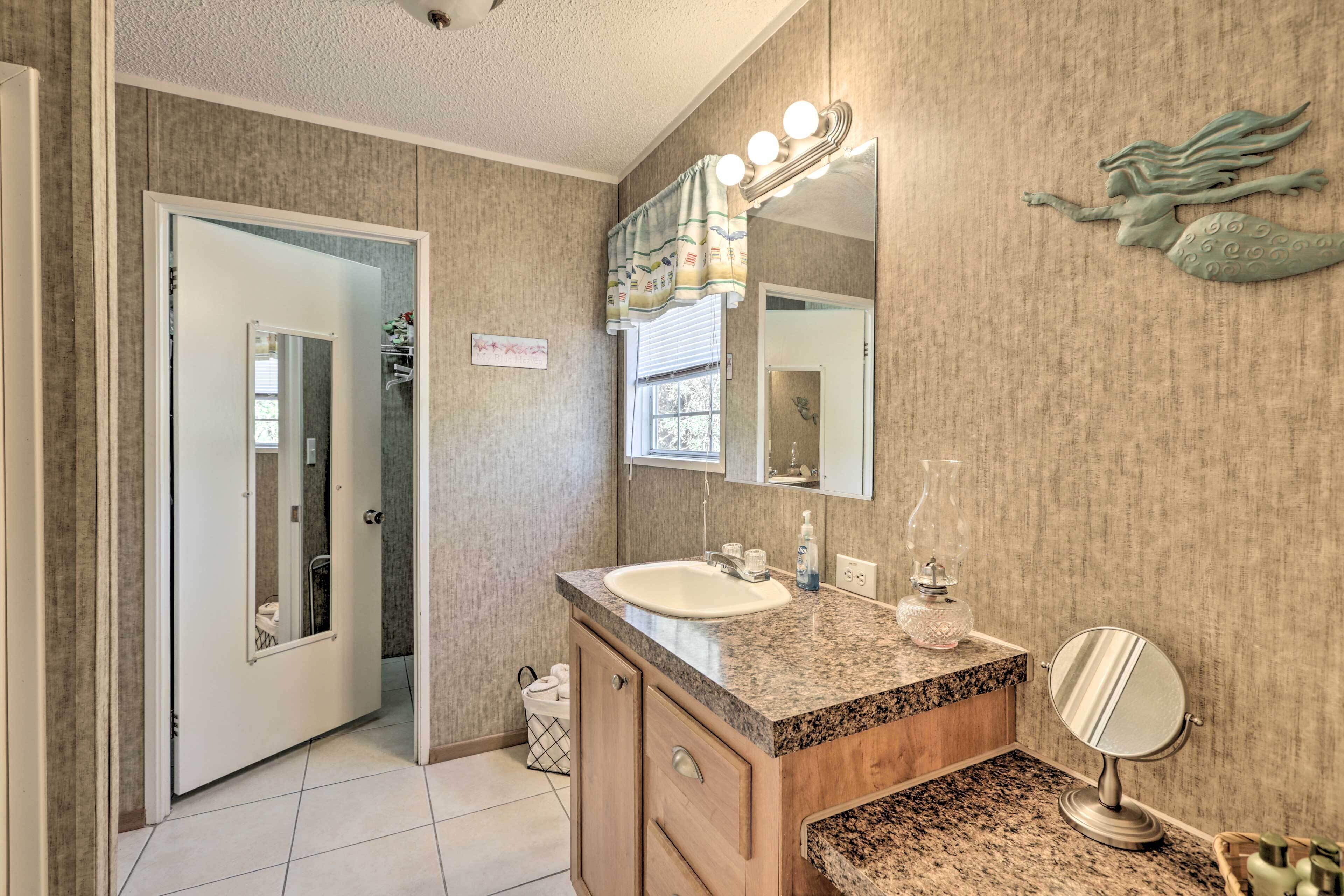 A bathroom with a sink, vanity, mirror, and lights.