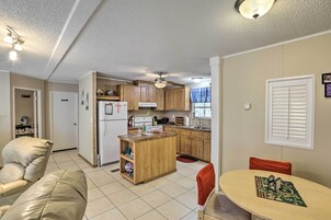 Cocina compacta con armarios de madera, una isla central y un comedor con mesa y sillas.