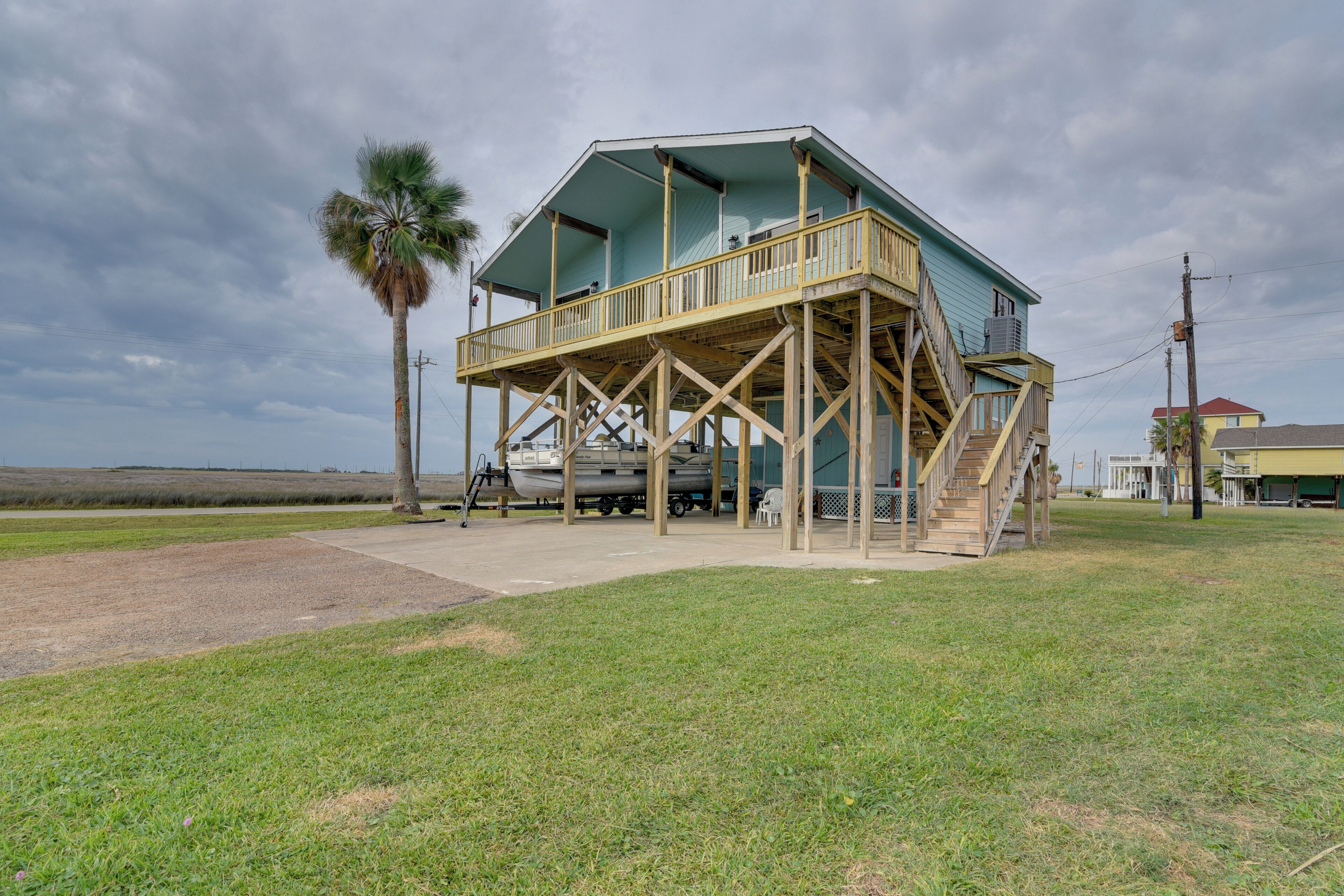 A two-story wooden house with a balcony, a staircase, and a boat docked outside.