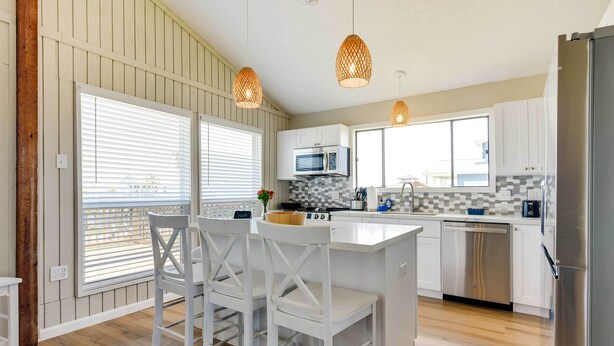 Una cocina moderna con armarios blancos, una isla central e iluminación colgante.