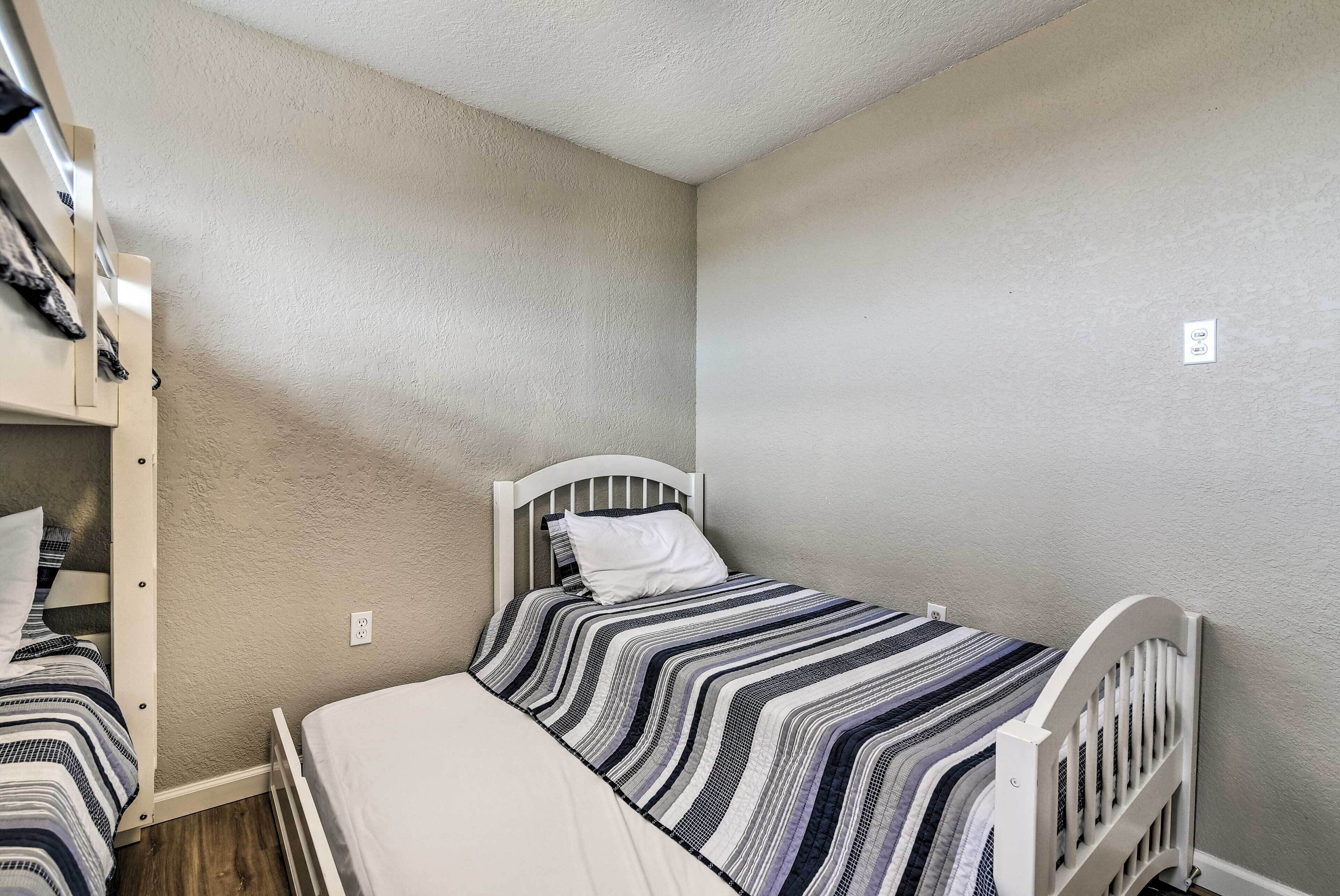 A small, single-bed room with a white headboard and a striped bedspread.