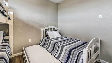 A small, single-bed room with a white headboard and a striped bedspread.