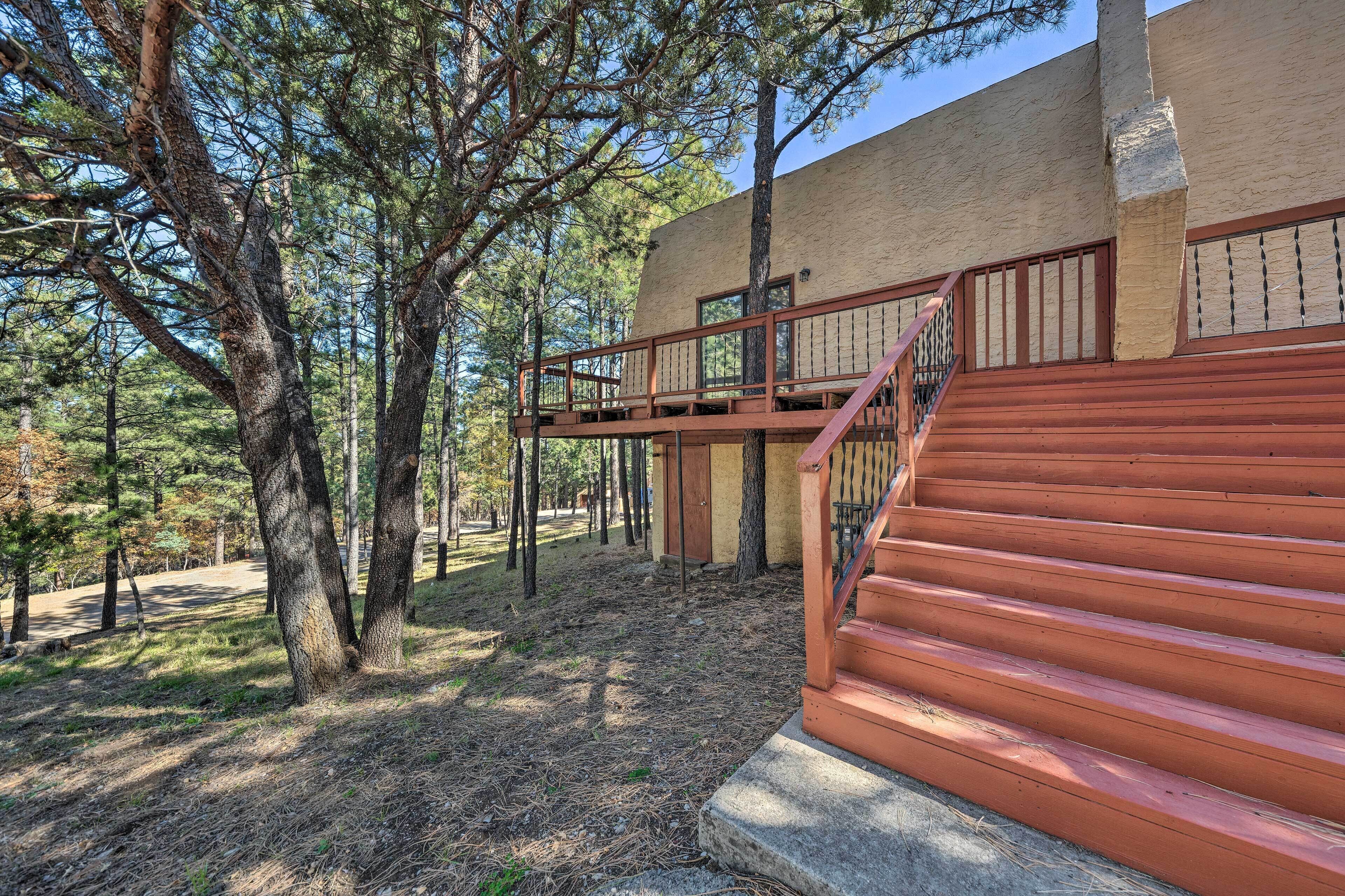 A building with a wooden staircase leading to a balcony, surrounded by trees.