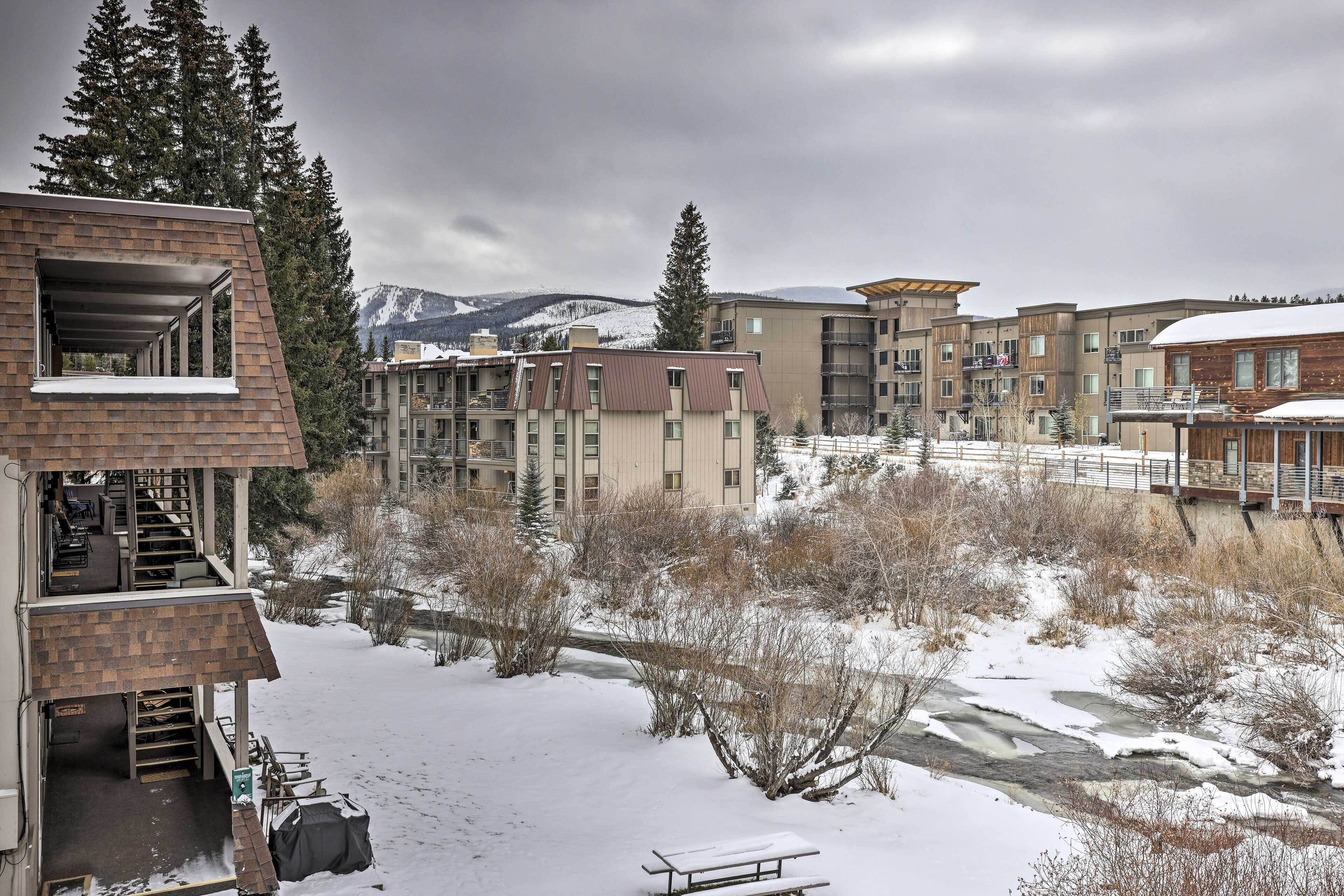 A multi-story building with a covered outdoor area, a snow-covered landscape, and a river.