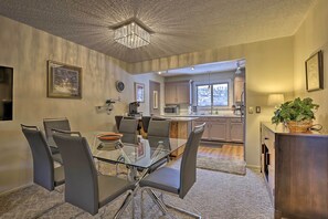 A modern kitchen with stainless steel appliances, a dining area with a glass table and chairs, and a view of the mountains through the window. - Condo on Fraser River < 4 Mi to Winter Park Resort (Winter Park)