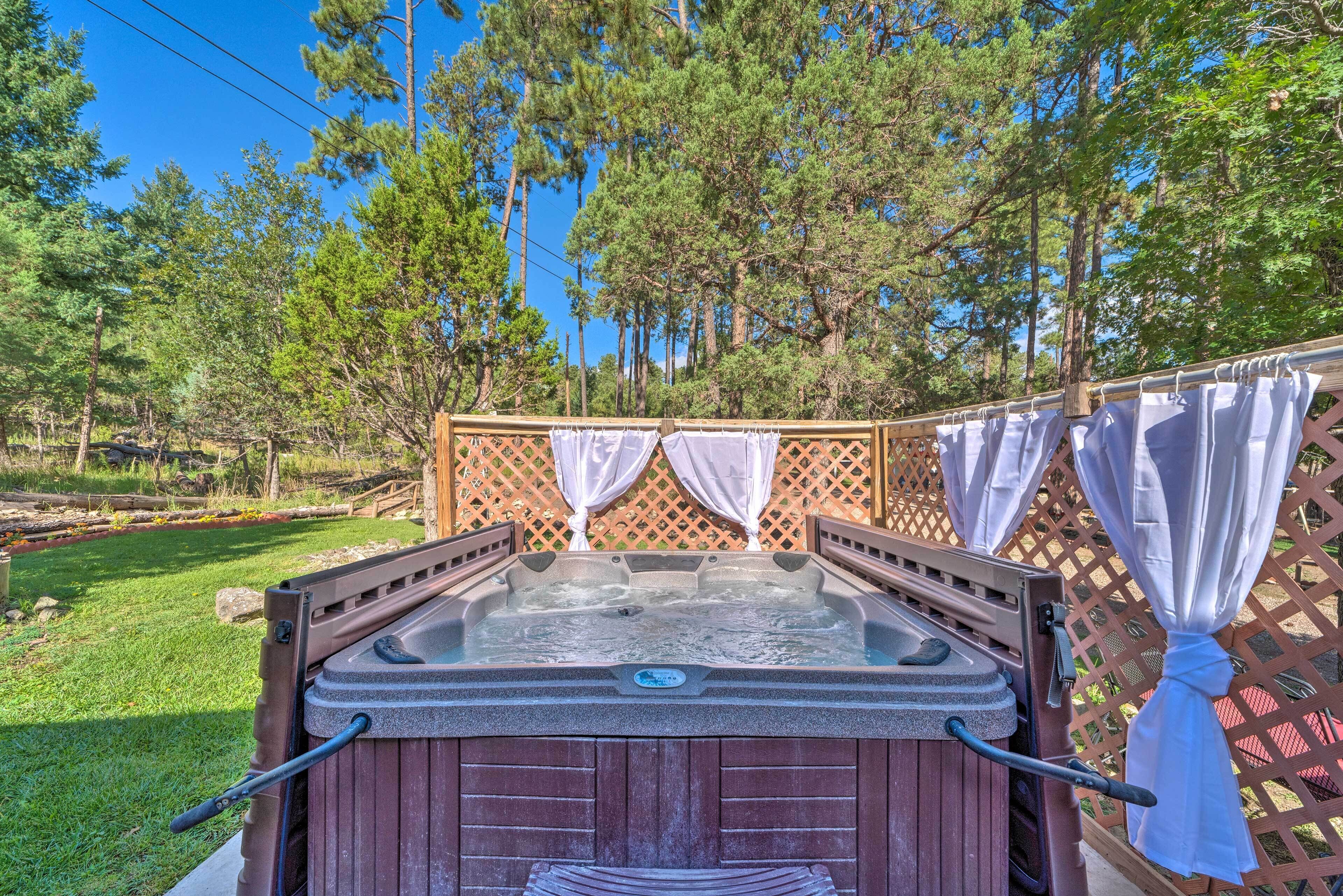 A hot tub with a wooden exterior, surrounded by a wooden deck and a lattice fence.