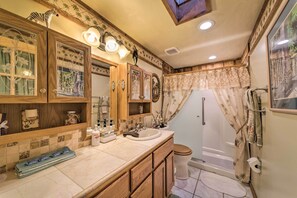 Un bagno con un mobile vanitario in legno, un lavandino, un WC e una zona doccia.
