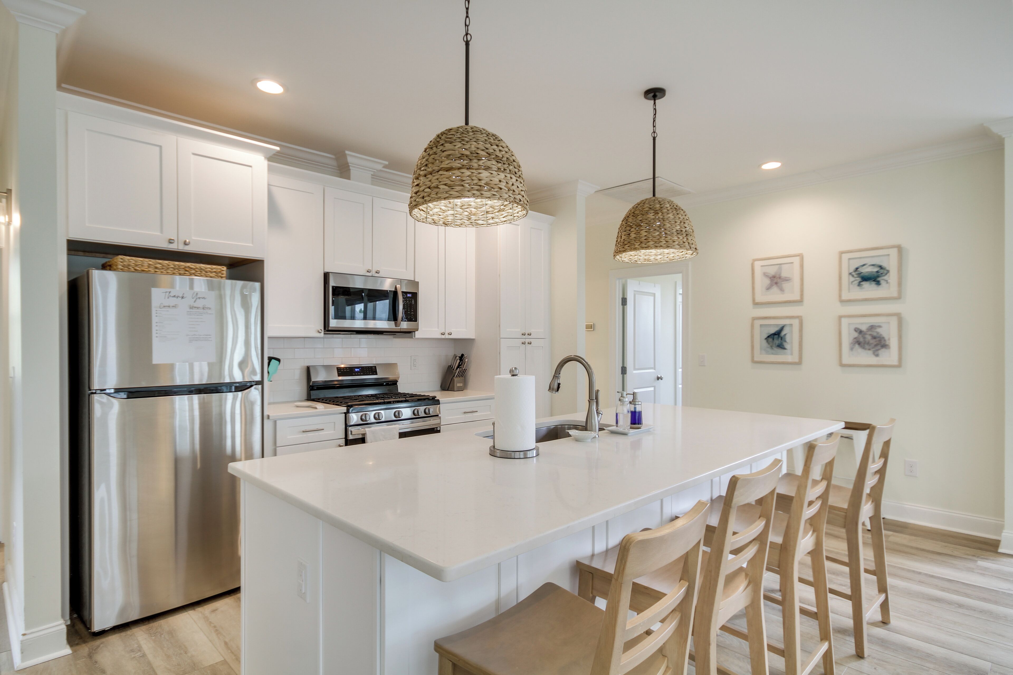 Una cocina moderna con armarios blancos, electrodomésticos de acero inoxidable y una isla central con taburetes de bar.