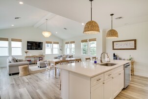A spacious living area with a large island, a dining table, and a kitchen with a dishwasher.