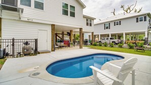 Ein Wohnhausgarten mit Schwimmbad, überdachter Terrasse und Garage.