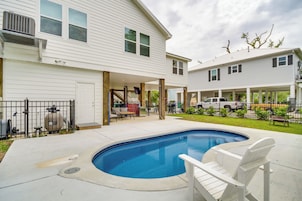 A residential backyard with a swimming pool, a covered patio, and a garage.