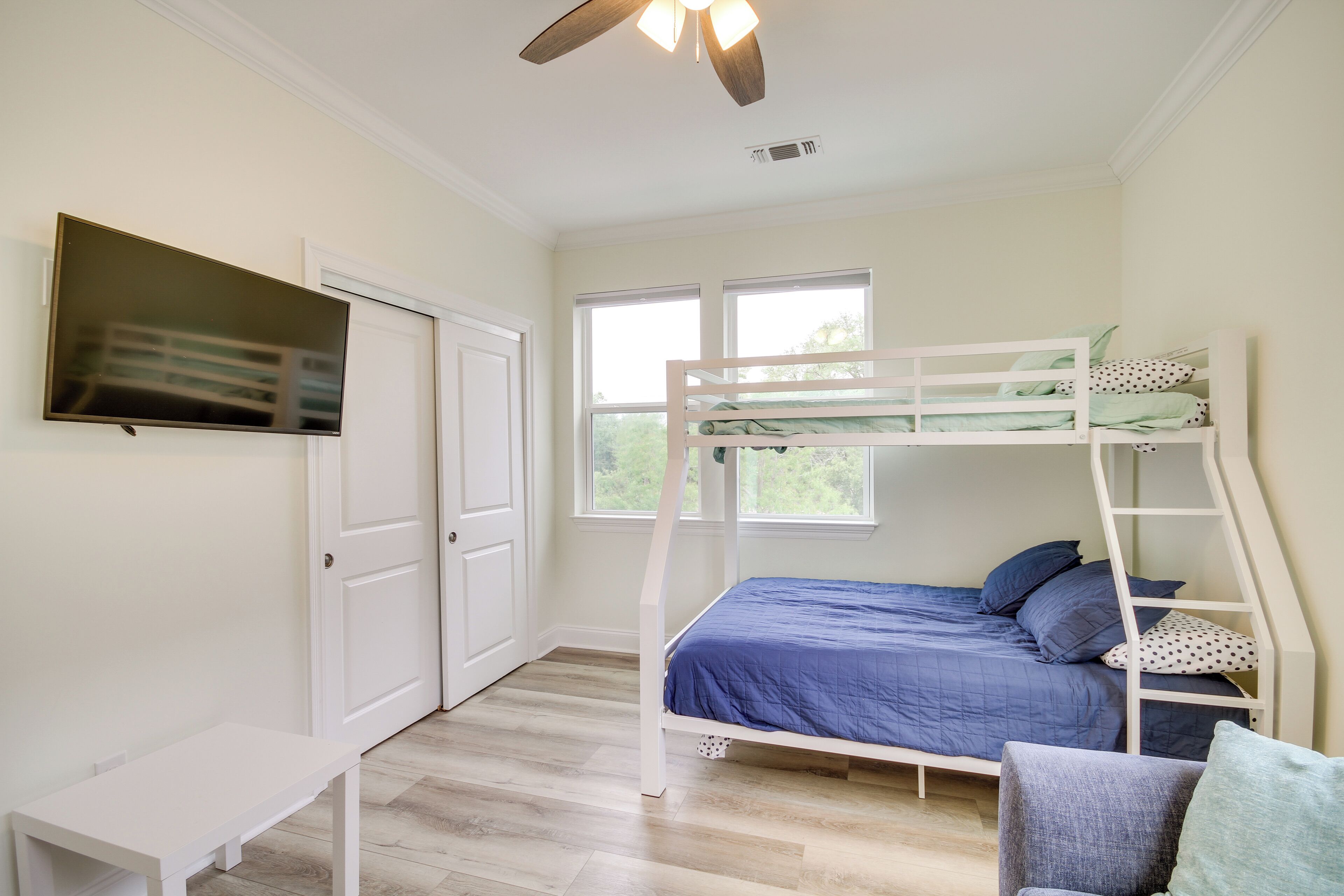 Ein Schlafzimmer mit Etagenbett, Schreibtisch, Fernseher und Deckenventilator.