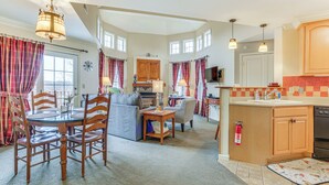A spacious living area with a dining table, chairs, and a sofa. There is a kitchen with wooden cabinets and a dishwasher. - Spacious Condo w/ View < 1 Mi to Mtn Creek Resort! (Vernon)