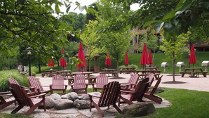 An outdoor seating area with Adirondack chairs and red umbrellas, surrounded by a stone pathway and greenery. - Spacious Condo w/ View < 1 Mi to Mtn Creek Resort! (Vernon)
