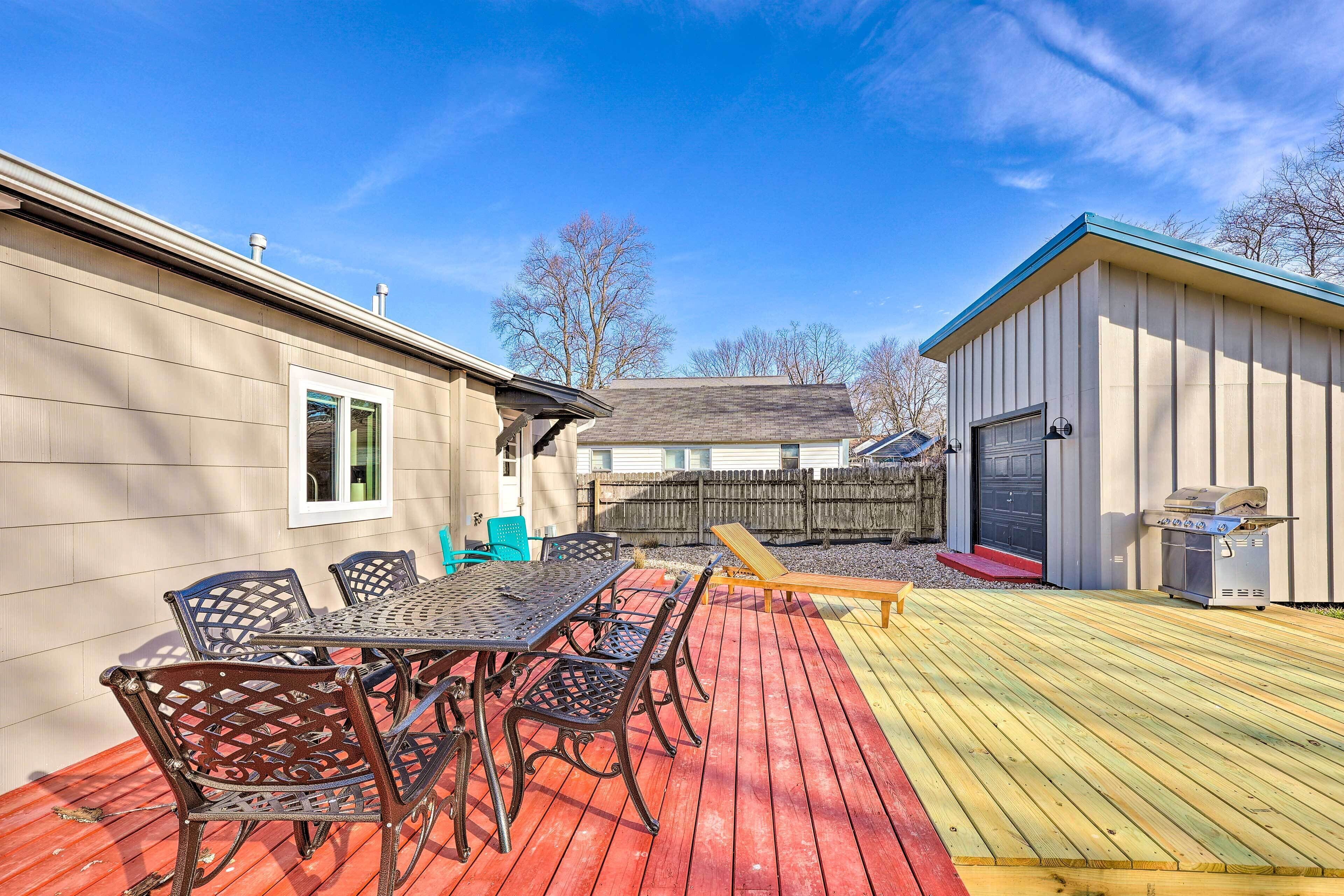 A deck with a table and chairs, a barbecue grill, and a shed.