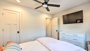 Un dormitorio con una cama, ventilador de techo, cómoda y espejo.