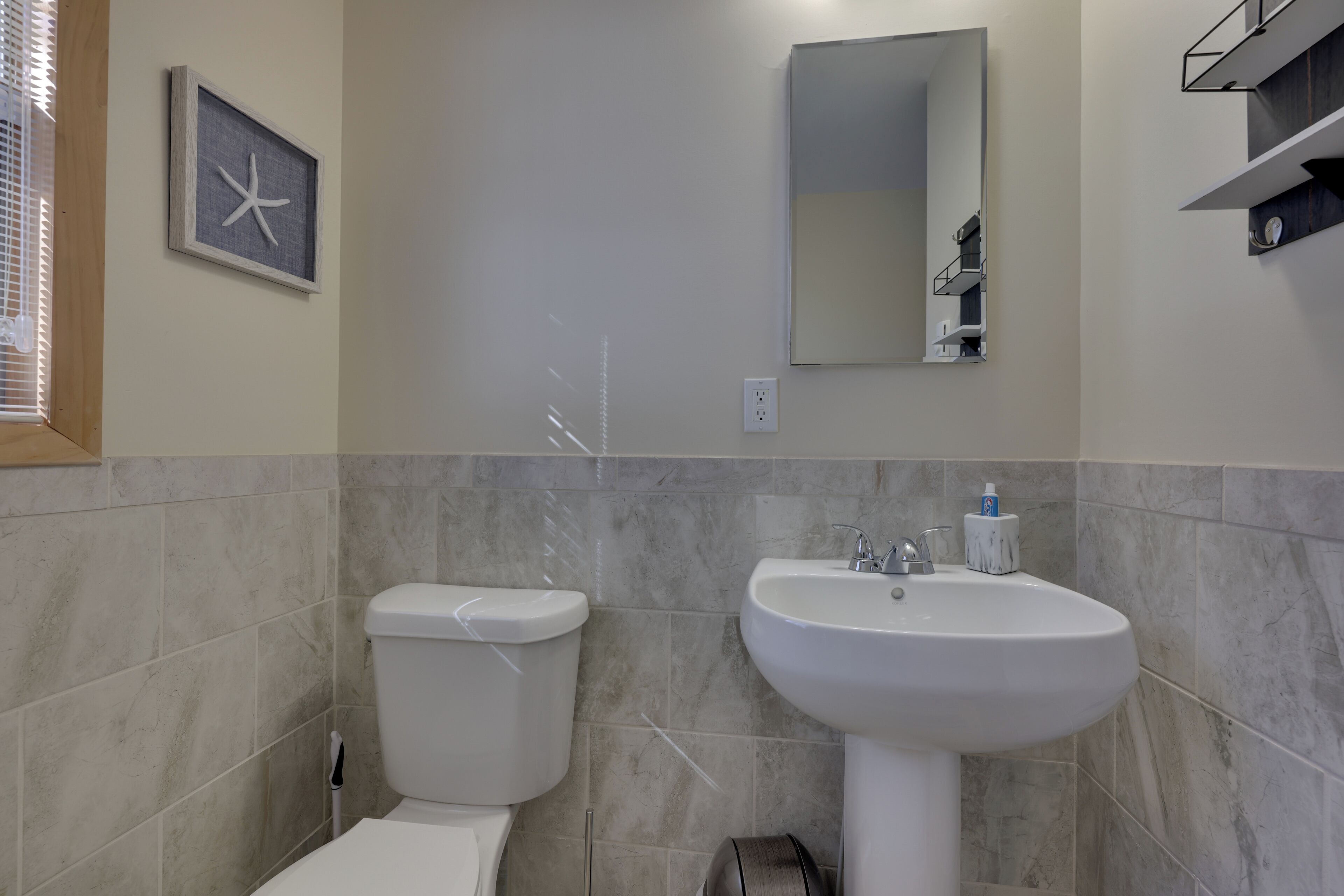 A bathroom with a toilet, sink, and a framed picture on the wall.